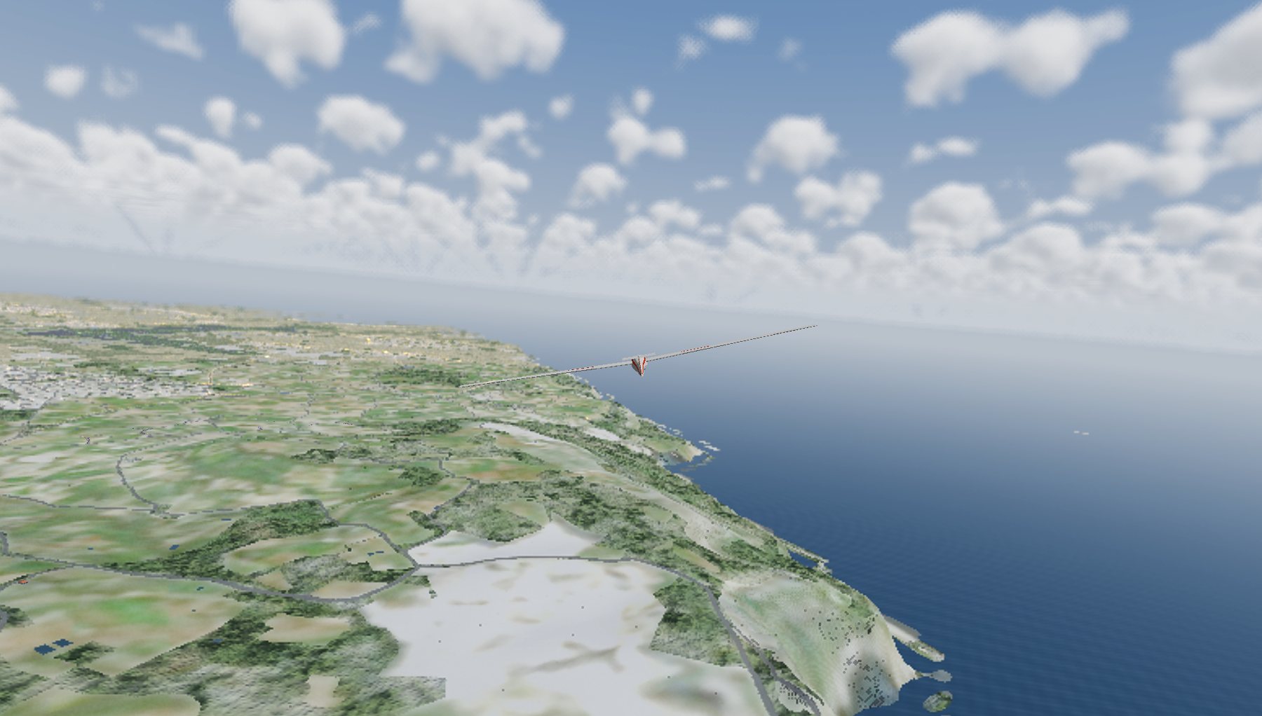 A glider crossing a coastline under scattered cumulus